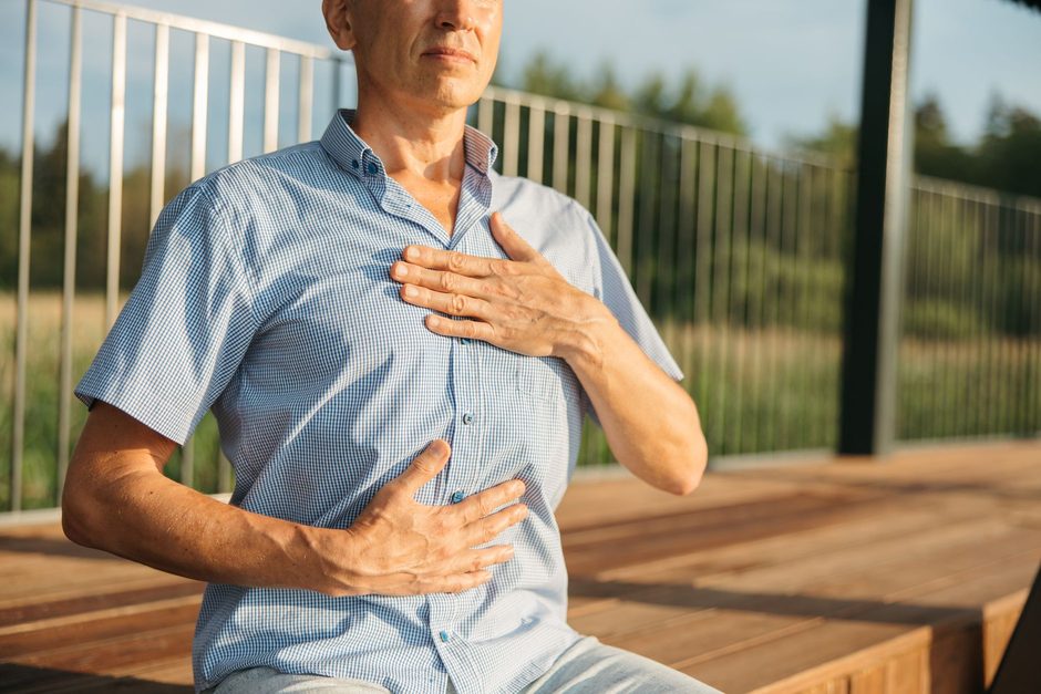 Mann macht eine Atemübung mit einer Hand auf der Brust und einer auf dem Bauch - Atemübungen gegen Angst