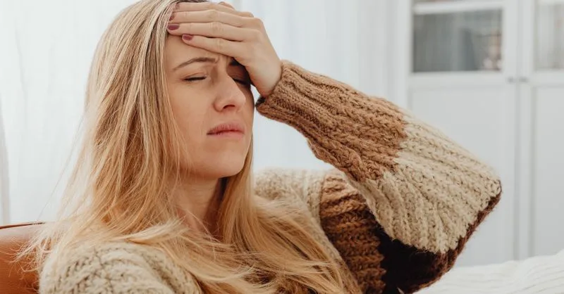 Frau macht am Schreibtisch eine kurze Pause und schließt die Augen, um Verspannung und Kopfschmerz durch Stress zu lösen