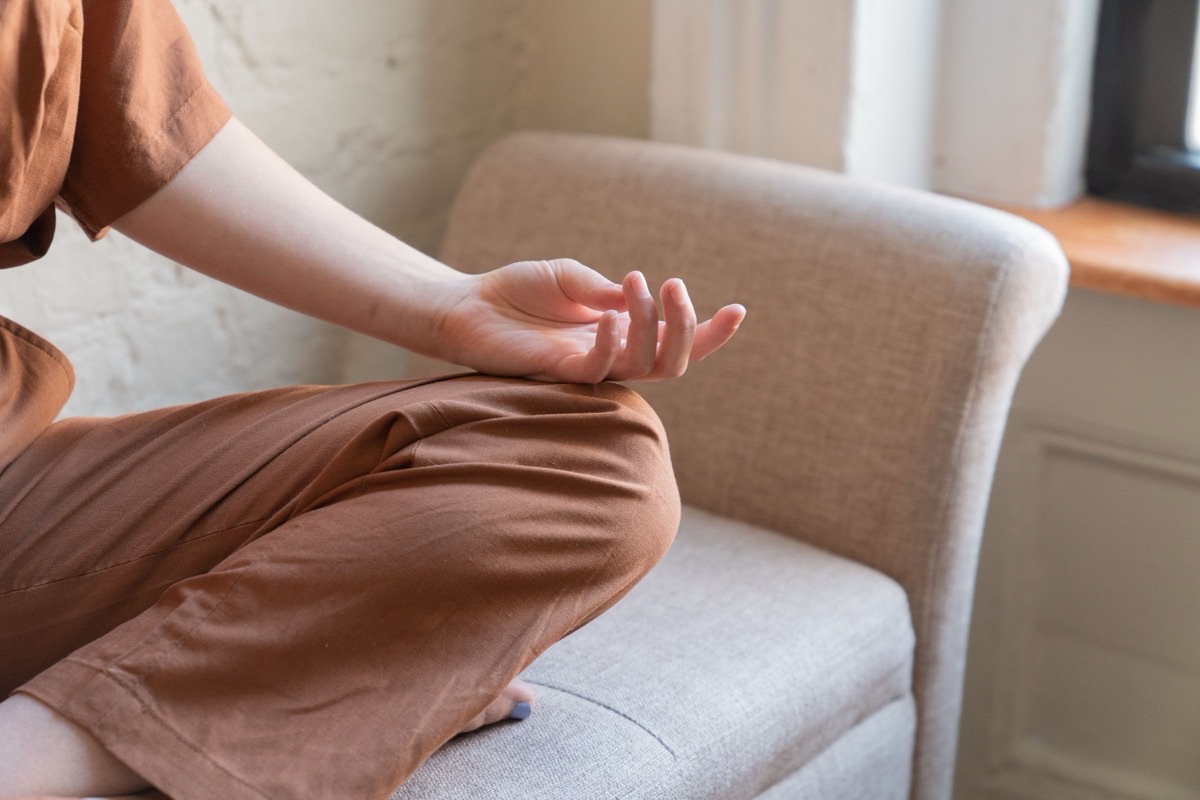 Person sitzt entspannt mit geschlossenen Augen in einem bequemen Sessel, Hände in einer ruhigen Haltung, Sinnbild für Meditation für Anfänger