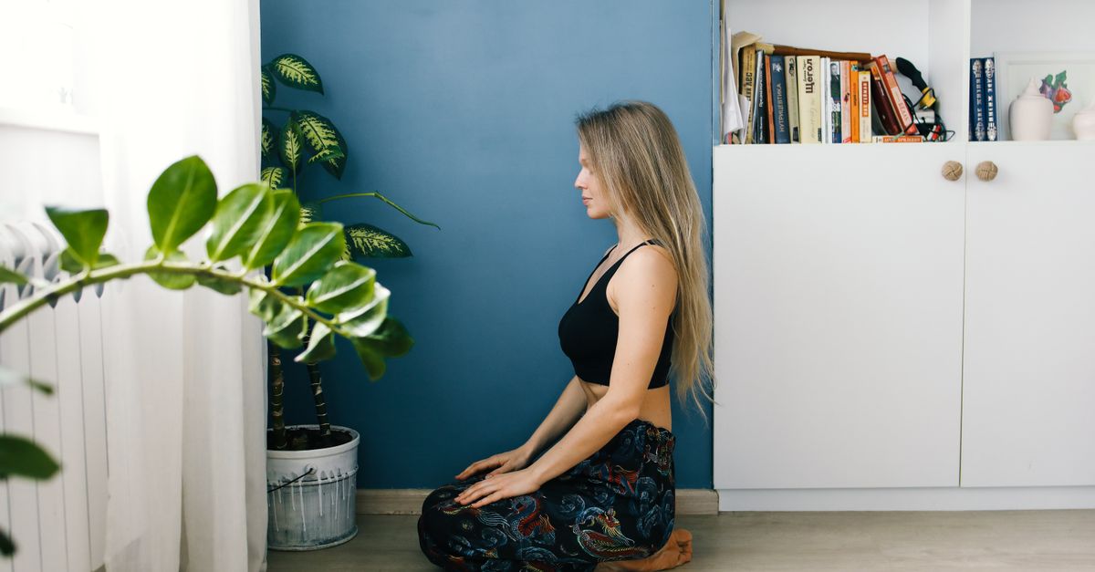 Meditation gegen innere Unruhe Frau meditiert ruhig zuhause zwischen Pflanzen, Sinnbild für Meditation gegen innere Unruhe