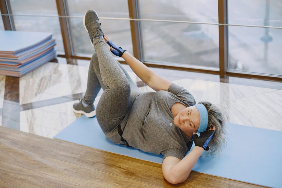 Frau dehnt sich entspannt auf einer Yogamatte - Progressive Muskelentspannung