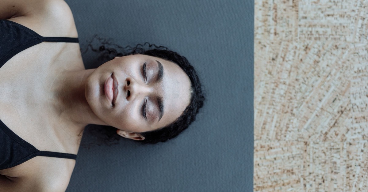 Yoga Nidra: 6 Schritte zur Praxis Frau liegt entspannt mit geschlossenen Augen auf einer Yogamatte, Sinnbild für die Tiefenentspannung bei Yoga Nidra